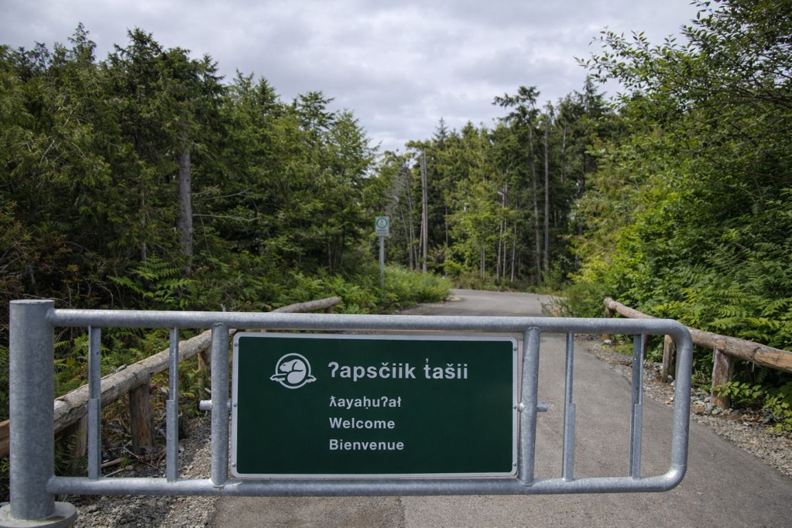 Forest pathway and welcome sign at ʔapsčiik t̓ašii trail in Pacific Rim area experienced during Tofino Tour Packages tour